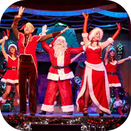 Papá Noel junto a dos bailarines en el Show de Navidad de PortAventura