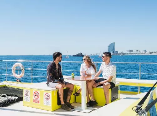 Tres amigos tomando bebidas en la cubierta del barco en Barelona